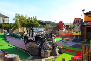 a playground with a jeep parked in a park at Golden Palm Resort - The Oasis - Coastal Caravan Breaks in Chapel Saint Leonards