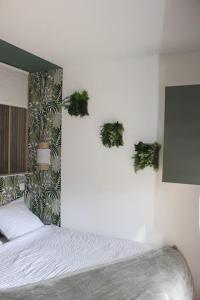 - une chambre avec un lit et deux plantes sur le mur dans l'établissement Le Parc, logement de charme avec SPA privatif - LE HAVRE, au Havre