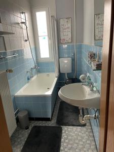 baño de azulejos azules con bañera y lavamanos en Holiday, en Wildflecken