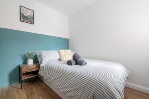 een slaapkamer met een bed met een gestreepte sprei en een tafel bij Bliss Stay Belfast: The Mount in Belfast