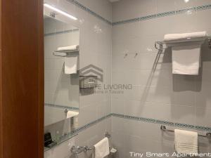 a bathroom with a toilet and a mirror and towels at Suites Marilia Apartments - Suite Livorno Holiday Home Group in Livorno
