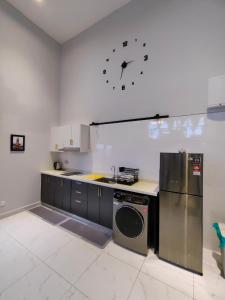 a kitchen with a refrigerator and a clock on the wall at Arte Cheras Duplex Suites in Kuala Lumpur
