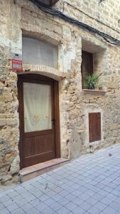 a stone building with a wooden door on it at La Fusteria d' Arnes in Arnés
