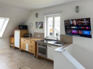 uma cozinha com um lavatório e uma televisão na parede em Flat 39 em Wiehl
