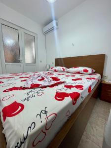 a bedroom with a bedspread with red roses on it at Guest House Luli in Sarandë +7 photos