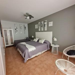 een slaapkamer met een bed en 2 stoelen en een plafondventilator bij Villa Fortuna in Caleta De Fuste