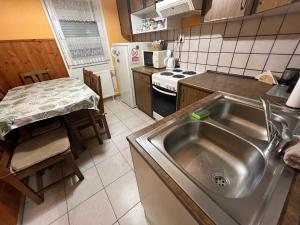 a kitchen with a stainless steel sink and a table at Atomcity Apartman in Paks