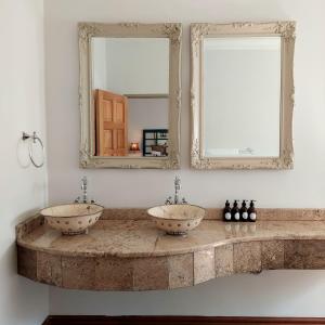 a bathroom with two sinks and two mirrors at Art and Soul Restaurant, Accommodation, French Bar and Art Gallery in Parys