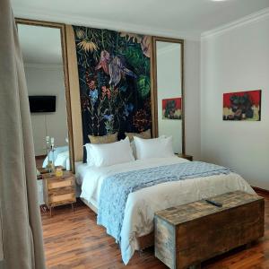 a bedroom with a large bed with a painting on the wall at Art and Soul Restaurant, Accommodation, French Bar and Art Gallery in Parys