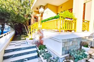 a house with a yellow railing and stairs with plants at Katrin's House in Katerini