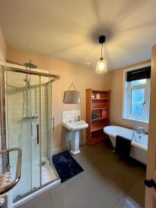a bathroom with a shower and a tub and a sink at The Snug in Fordingbridge