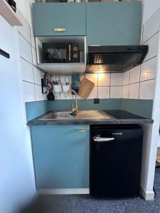 uma pequena cozinha com armários azuis e um lavatório em Joli Studio avec cuisine 1 lit double de qualité piscine et parking gratuit em Aix-en-Provence