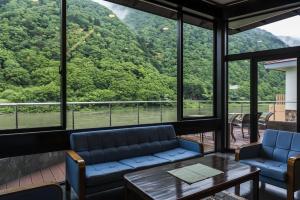 um quarto com uma mesa e cadeiras e uma grande janela em Takamiya Ryokan Beni em Tozawa