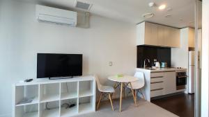 a kitchen with a tv and a table with chairs at Sky Stars Park Apartment in Auckland