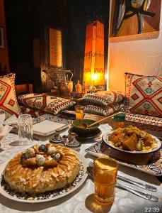 - une table avec des assiettes de nourriture et une tarte dans l'établissement Le Petit Riad Maison d'hôtes, à Ouarzazate