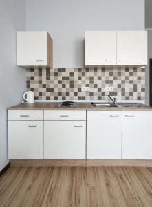 una cocina con armarios blancos y fregadero en Elys Aparthotel in Leipzig - Vollausgestattete Apartments mit Netflix, en Leipzig