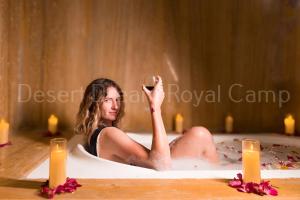 una donna seduta nella vasca da bagno con un bicchiere di vino di Desert Dream Royal Camp with Pool a Jaisalmer