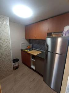 La cuisine est équipée d'un réfrigérateur en acier inoxydable et de placards en bois. dans l'établissement logement tout confort marina or, à Oropesa del Mar