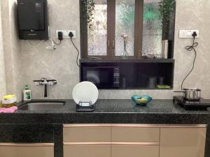 a kitchen counter with a sink and a microwave at Casa Quatro in Mumbai