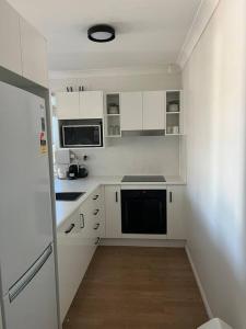 een kleine keuken met witte kasten en een koelkast bij Apartment on Henry in North Ward