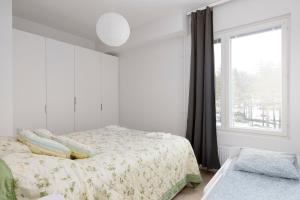 a white bedroom with a bed and a window at New 2BR design home with sauna Espoo Park in Espoo