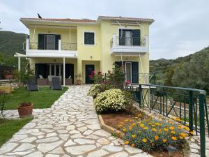 een geel huis met een balkon en een aantal bloemen bij 350m Above Sea in Vasiliki