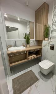 a bathroom with a sink and a toilet and a mirror at Apartament Whiteblue Dream 2 Kołobrzeg z ogródkiem & sauna & fitness & bawialnia dla dzieci in Kołobrzeg