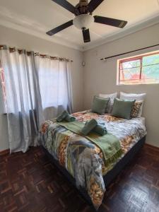 a bedroom with a bed with a ceiling fan at South Coast Suburban Escape in Kingsburgh