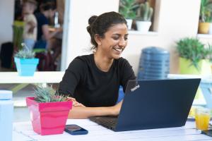 a woman sitting at a table with a laptop computer at Safestay Pisa Centrale in Pisa
