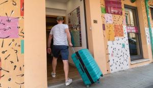 a man walking into a building with a suitcase at Safestay Pisa Centrale in Pisa