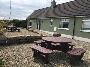a picnic table and benches in front of a house at Causeway Coast Country Cottage, Pet-friendly in Ballycastle +11 photos