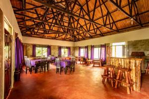 KapchorwaにあるMise cave lodgeのテーブル、椅子、紫色の椅子が備わる広い客室です。