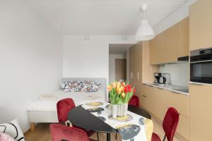 a dining room table with red chairs and a kitchen at Sea View Design Studio near metro in Espoo in Espoo