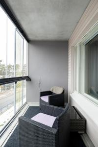 Zimmer mit 2 Stühlen, einem Tisch und Fenstern in der Unterkunft Sea View Design Studio near metro in Espoo
