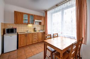 a kitchen with a wooden table and a white refrigerator at Apartmány u Adama in Rokytnice v Orlických Horách