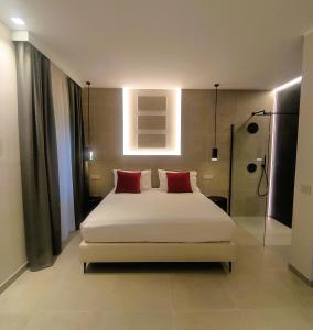 a bedroom with a white bed with two red pillows at Su Coru 2 - Deluxe Studio in the Heart of Cagliari in Cagliari