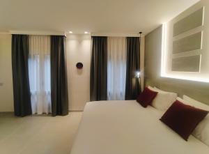 a bedroom with a large white bed with red pillows at Su Coru 2 - Deluxe Studio in the Heart of Cagliari in Cagliari