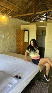 a woman sitting on a bed in a room at 101 wake park in Mandrem