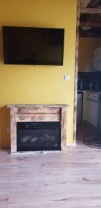 a fireplace with a flat screen tv on a yellow wall at Dolina Rosy in Ustrzyki Dolne