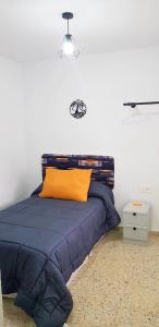 a bedroom with a blue bed with an orange pillow at Alojamiento Maria in Pinos Genil