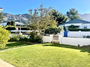 a backyard with a white fence and grass at Franschhoek- African dream in Franschhoek