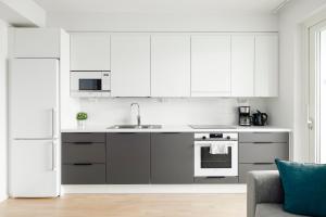 Modern LUXUS 3BR apartment Helsinki Tripla في هلسنكي: مطبخ فيه دواليب بيضاء وثلاجة بيضاء
