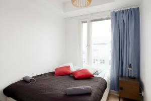 Schlafzimmer mit einem Bett mit roten Kissen und einem Fenster in der Unterkunft Modern LUXUS 3BR apartment Helsinki Tripla in Helsinki