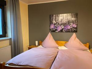1 cama con sábanas blancas y almohadas rosas en Ferienwohnung Burgberg, en Stadtkyll