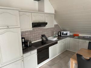 a white kitchen with white cabinets and a microwave at Ferienwohnung Klara in Meßstetten
