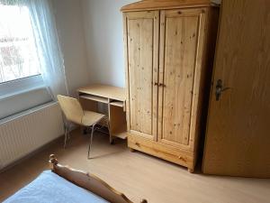 a bedroom with a desk and a wooden cabinet at Ferienwohnung Klara in Meßstetten