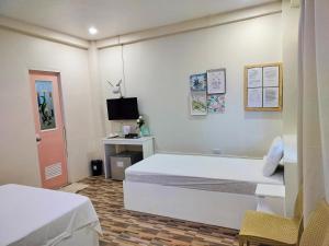 Swakihan Guest House في سيكويجور: غرفة نوم بسرير ابيض ومكتب