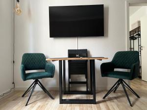 a table with two chairs and a television on a wall at 100m E-Ladestation - max 4 pers - Düsseldorf - Ruhrgebiet - Pilgerstätte in Velbert