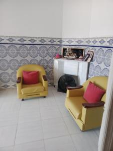 a living room with two yellow chairs and a fireplace at Maison pied dans l'eau Bainem Alger in Baïnem Falaise