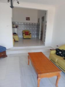 a living room with a wooden table and yellow chairs at Maison pied dans l'eau Bainem Alger in Baïnem Falaise